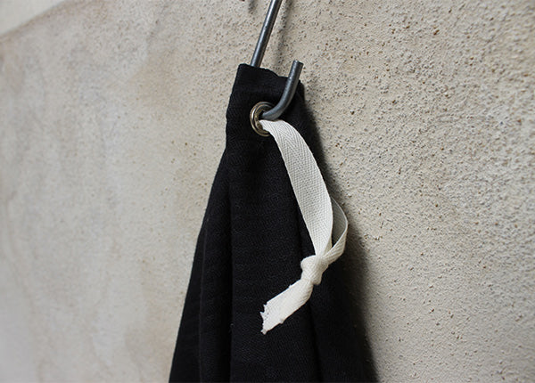 détail oeillet en aluminium d'un essuie-main en lin, métis ou coton anciens damassés teint en couleur noire